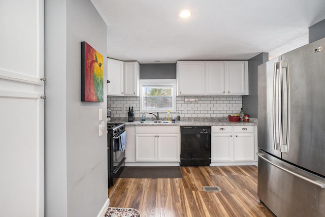 kitchen with black appliances, white cabinetry, tasteful backsplash, and sink