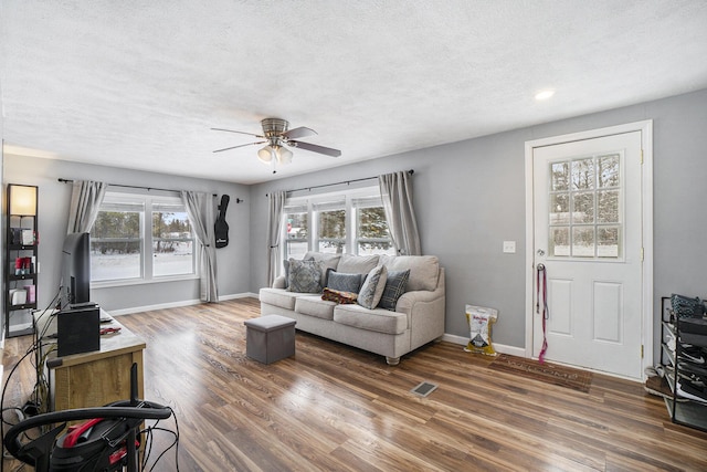 living room featuring ceiling fan, dark wood-type flooring, and a textured ceiling