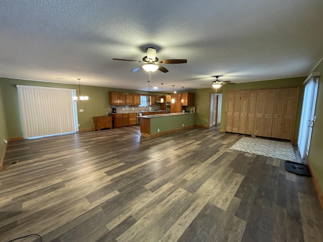 unfurnished living room featuring dark hardwood / wood-style flooring, ceiling fan with notable chandelier, and a textured ceiling