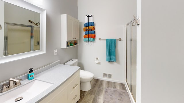 bathroom with a shower with shower door, wood-type flooring, toilet, and vanity