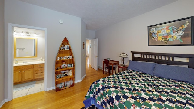 bedroom with sink, ensuite bathroom, and light wood-type flooring