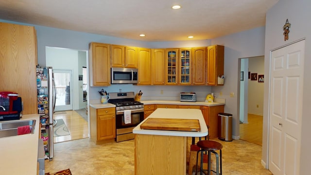 kitchen with sink, a center island, appliances with stainless steel finishes, and a kitchen breakfast bar