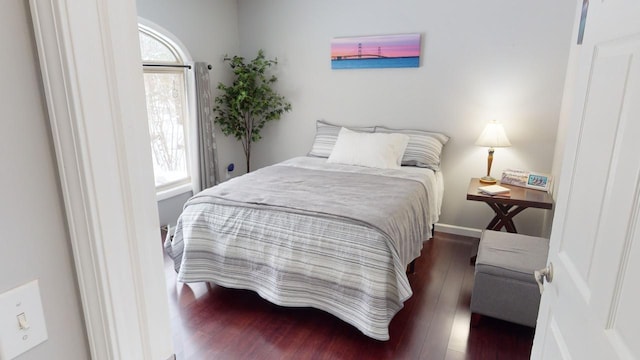 bedroom with dark hardwood / wood-style floors and multiple windows