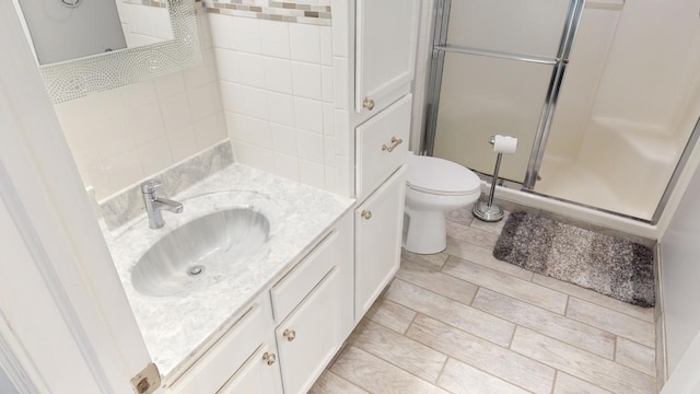 bathroom featuring vanity, toilet, and a shower with shower door