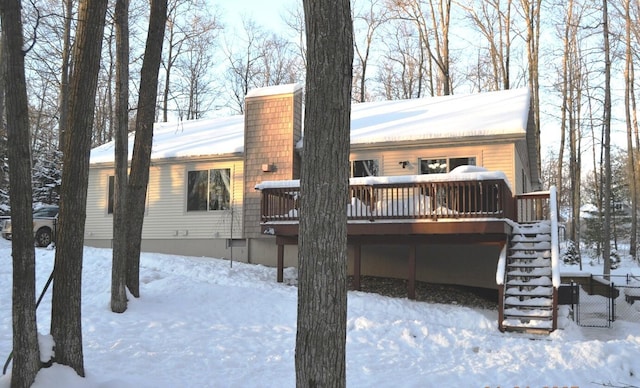 snow covered back of property featuring a wooden deck