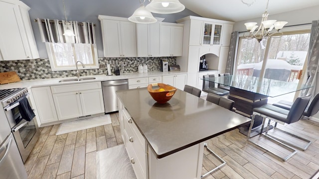 kitchen with white cabinetry, sink, stainless steel appliances, and a center island