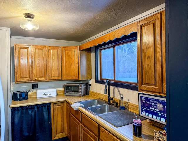 kitchen with sink, a textured ceiling, and decorative backsplash