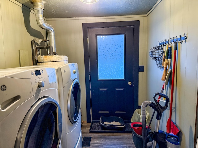 laundry area with wooden walls, washer and dryer, dark wood-type flooring, and a textured ceiling