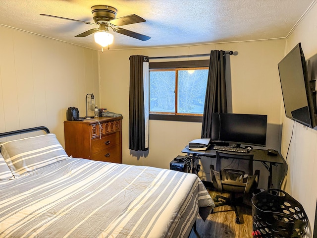 bedroom featuring ceiling fan, hardwood / wood-style floors, and a textured ceiling