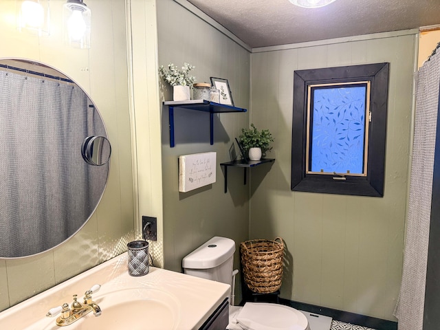 bathroom with vanity, toilet, a textured ceiling, and wood walls