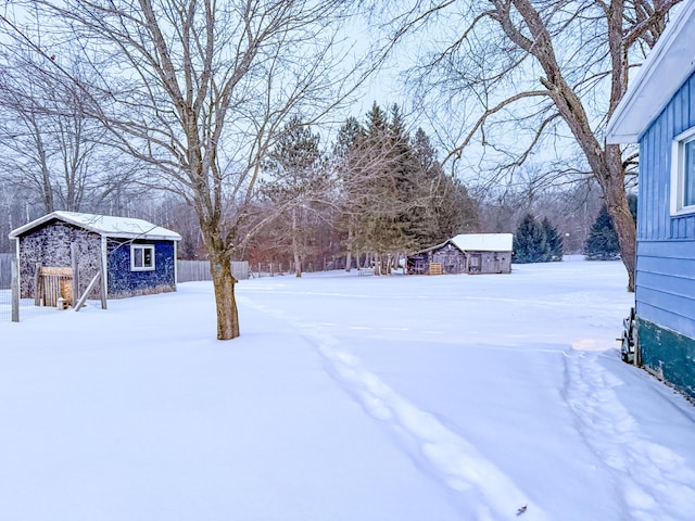 yard layered in snow featuring a storage shed