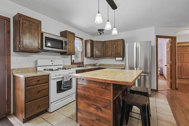 kitchen featuring hanging light fixtures, stainless steel appliances, a center island, and light tile patterned flooring