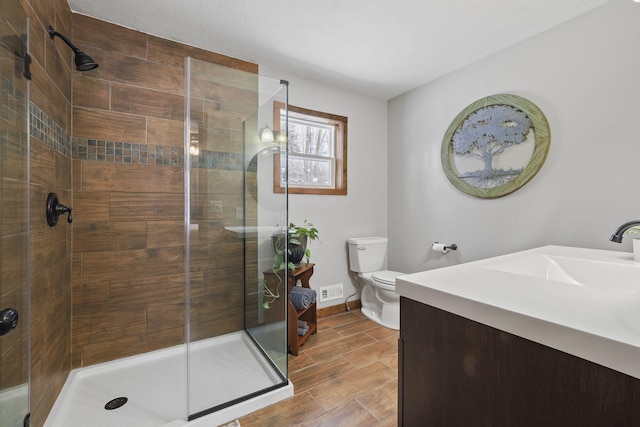 bathroom featuring a shower with door, vanity, and toilet