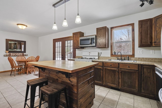 kitchen featuring french doors, sink, white range with gas stovetop, hanging light fixtures, and light tile patterned floors