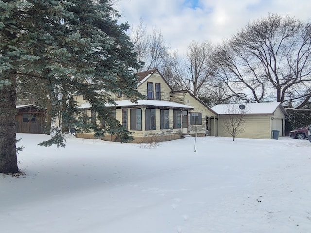 snow covered rear of property featuring a garage