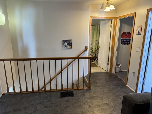 corridor featuring a chandelier and dark carpet