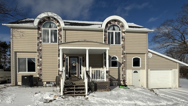 view of front of home with cooling unit, a garage, and covered porch