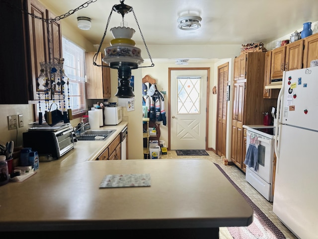 kitchen with sink, white appliances, and kitchen peninsula