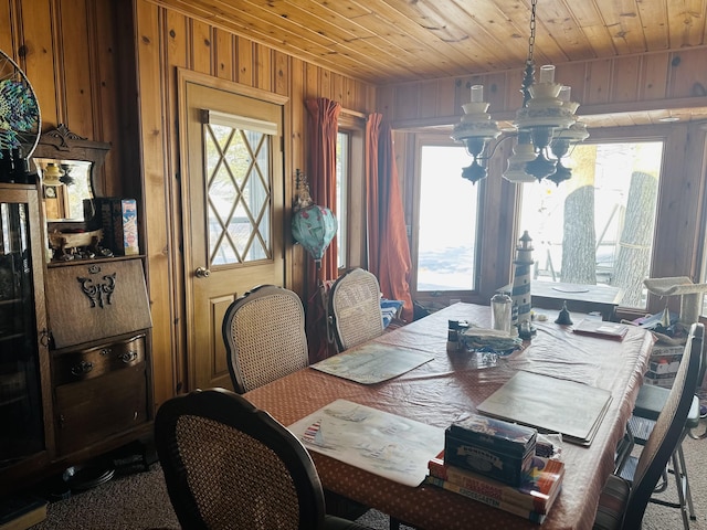 dining space featuring a notable chandelier, wood ceiling, and wood walls