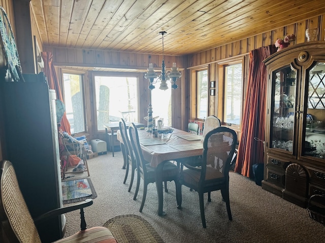 dining area with wood ceiling, wooden walls, a chandelier, and carpet