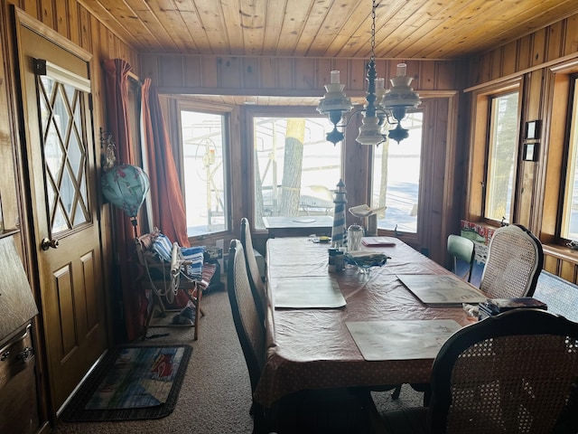 dining area with an inviting chandelier, wooden walls, carpet floors, and wooden ceiling