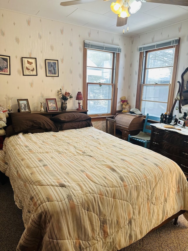 carpeted bedroom featuring multiple windows and ceiling fan