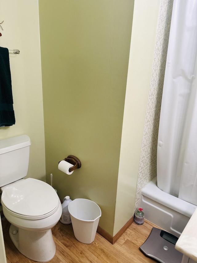 bathroom with hardwood / wood-style floors, shower / bath combo with shower curtain, and toilet