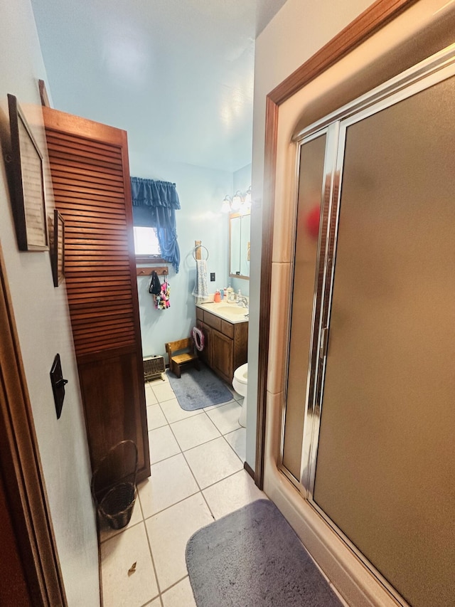 bathroom featuring tile patterned flooring, vanity, an enclosed shower, and toilet