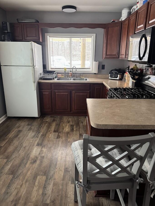 kitchen featuring sink, gas range, dark wood-type flooring, and white fridge