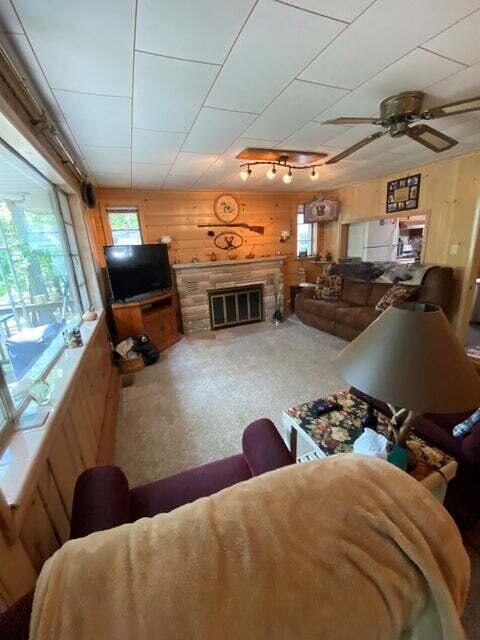 living room featuring ceiling fan and wooden walls