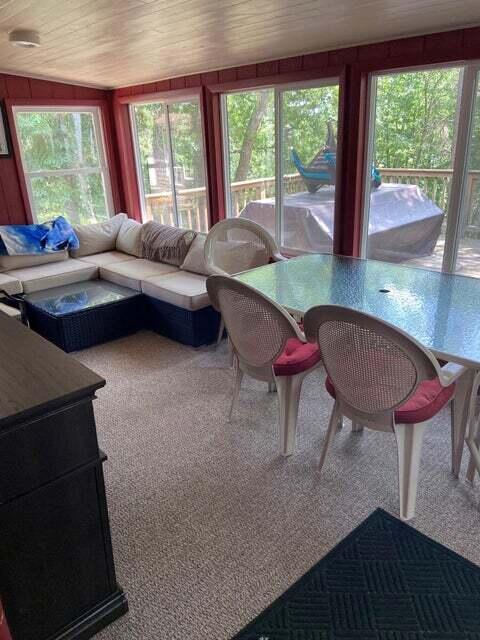 carpeted living room featuring lofted ceiling, a healthy amount of sunlight, wooden ceiling, and wooden walls