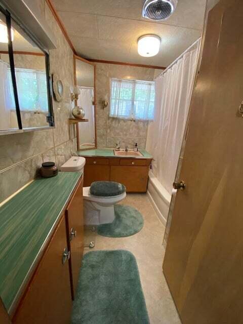 full bathroom with tile walls, vanity, crown molding, and toilet