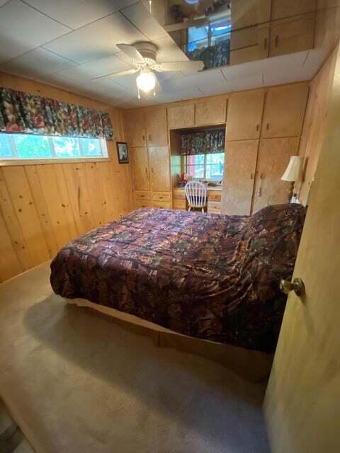 bedroom featuring carpet flooring, ceiling fan, and wood walls