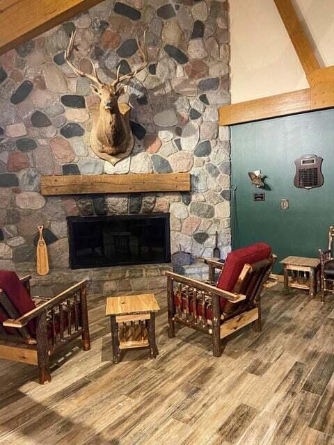 sitting room with beam ceiling, a fireplace, high vaulted ceiling, and wood-type flooring