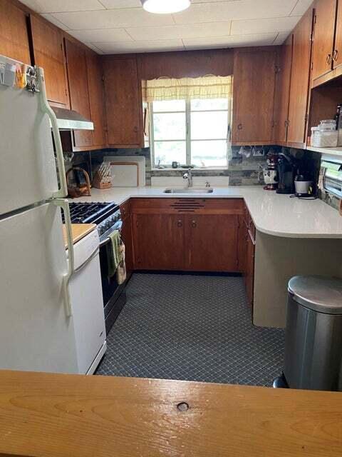 kitchen with sink, decorative backsplash, range with gas stovetop, and white refrigerator