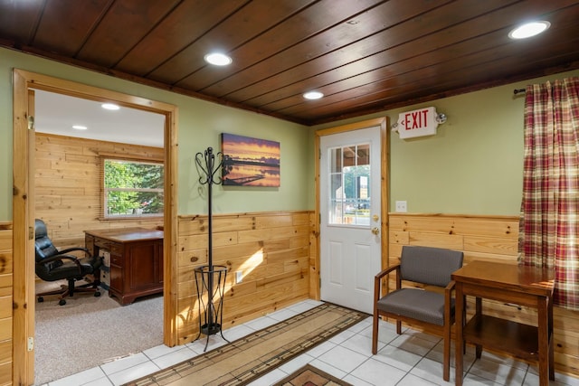 entryway with ornamental molding, wooden ceiling, light carpet, and wood walls