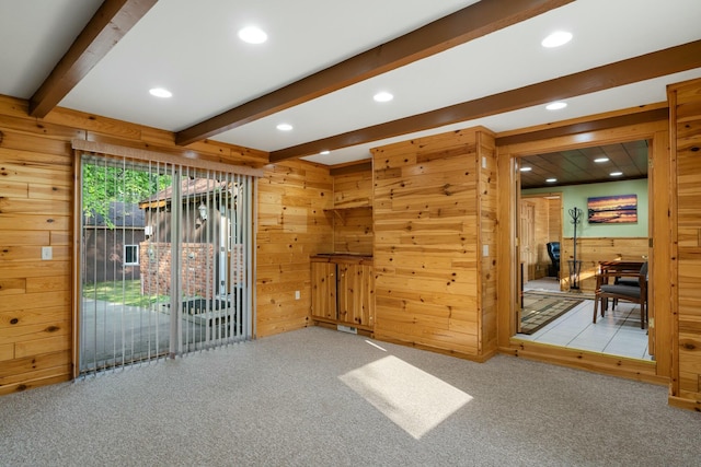 living room featuring light colored carpet, beam ceiling, and wood walls