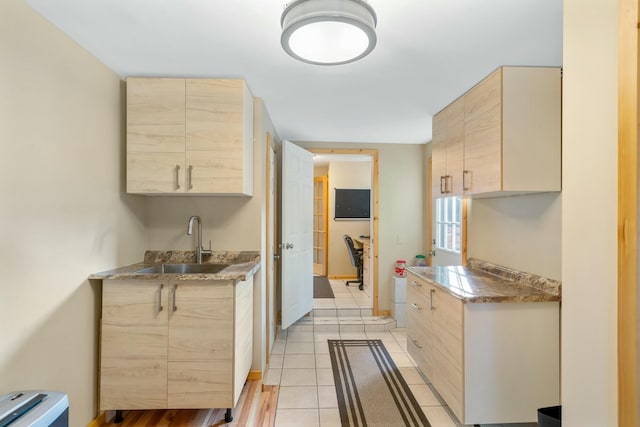 kitchen with light brown cabinetry, sink, and light tile patterned floors