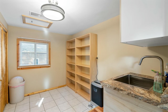 kitchen featuring stone counters, sink, light tile patterned floors, and light brown cabinetry