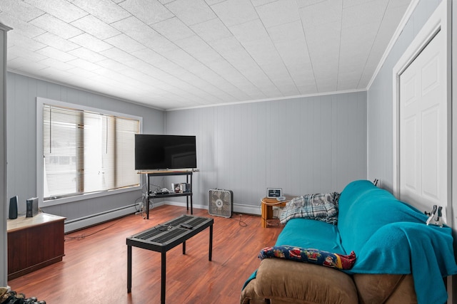 living room with ornamental molding, wood-type flooring, and a baseboard heating unit