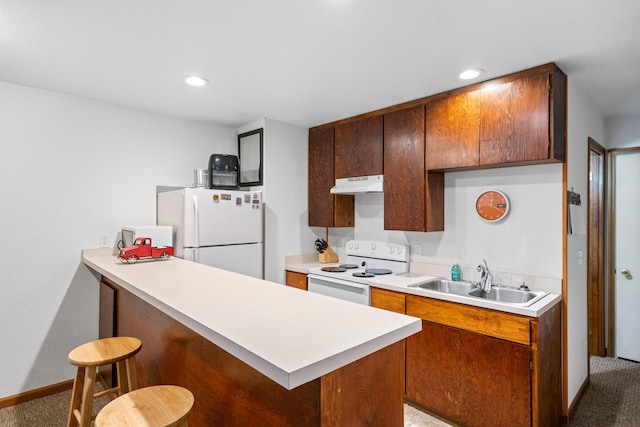 kitchen featuring white appliances, carpet floors, a kitchen bar, and sink