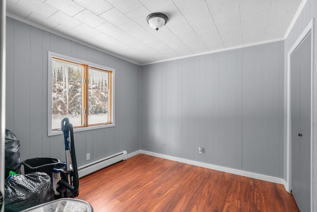 interior space with a baseboard heating unit, crown molding, and wood-type flooring