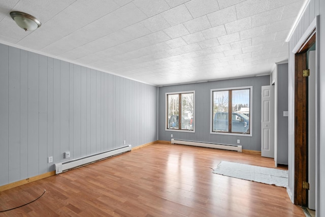 empty room featuring a baseboard radiator and light hardwood / wood-style floors