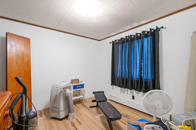 workout area featuring wood-type flooring and crown molding