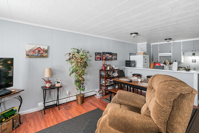 living room featuring ornamental molding, a baseboard heating unit, and hardwood / wood-style floors