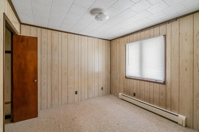 unfurnished room with a baseboard radiator, carpet, ornamental molding, and wood walls