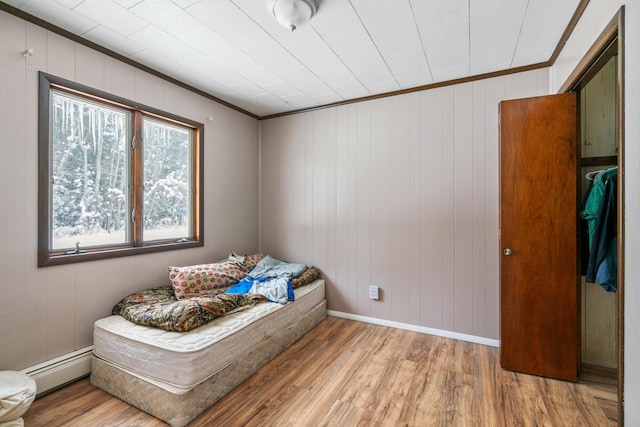 bedroom featuring a baseboard heating unit, crown molding, and wood-type flooring