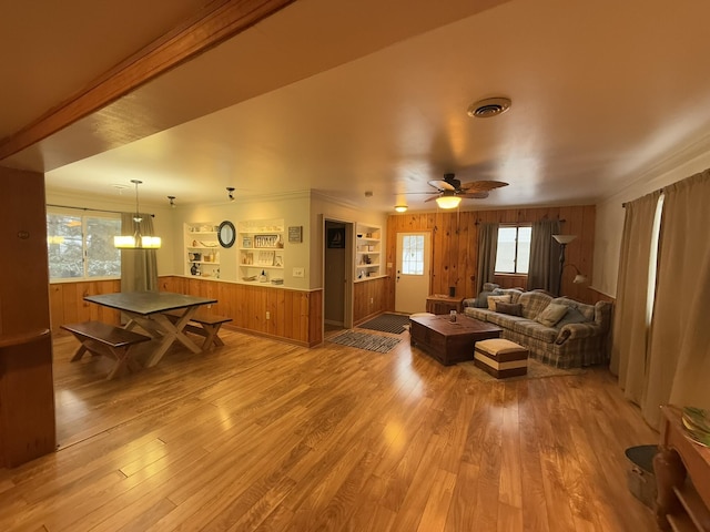 living room with hardwood / wood-style floors, wooden walls, a healthy amount of sunlight, and ceiling fan