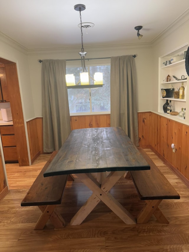 dining room featuring ornamental molding, built in features, and light hardwood / wood-style floors