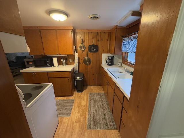 kitchen with sink, electric range, and light wood-type flooring